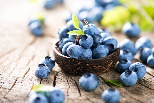 New Research: Why Pairing Antioxidants With Your Sunscreen Matters. Close up of bowl of antioxidant-rich  blueberries on wooden table