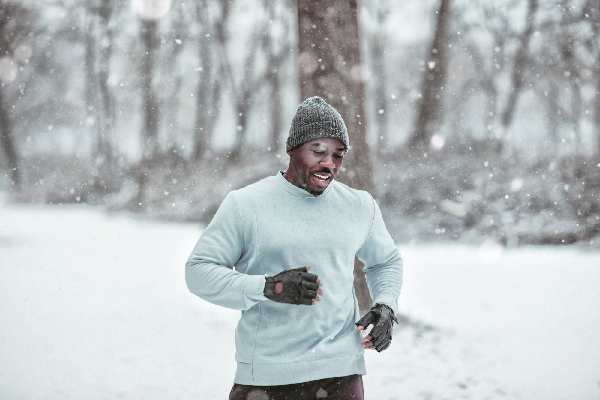 Athletic Black man running in winter snow wearing gray beanie