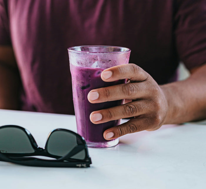 3 Antioxidant Smoothies for Brighter, More Resilient Skin. Man pouring healthy, green smoothie into glass