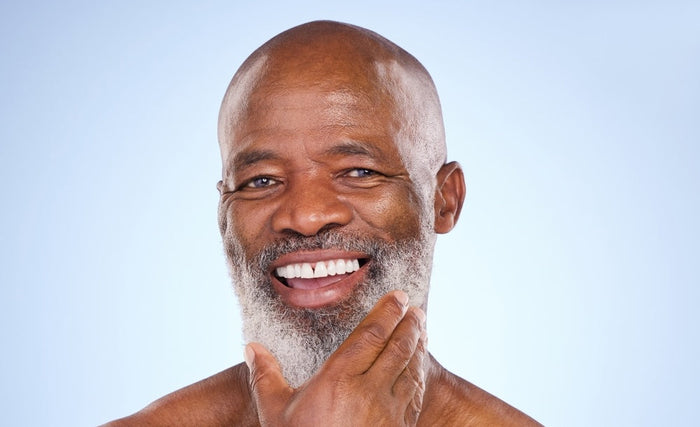 Black Skin and Anti-Aging: How to Keep Your Skin Looking Young and Healthy. Close up image of handsome mature black man smiling towards camera