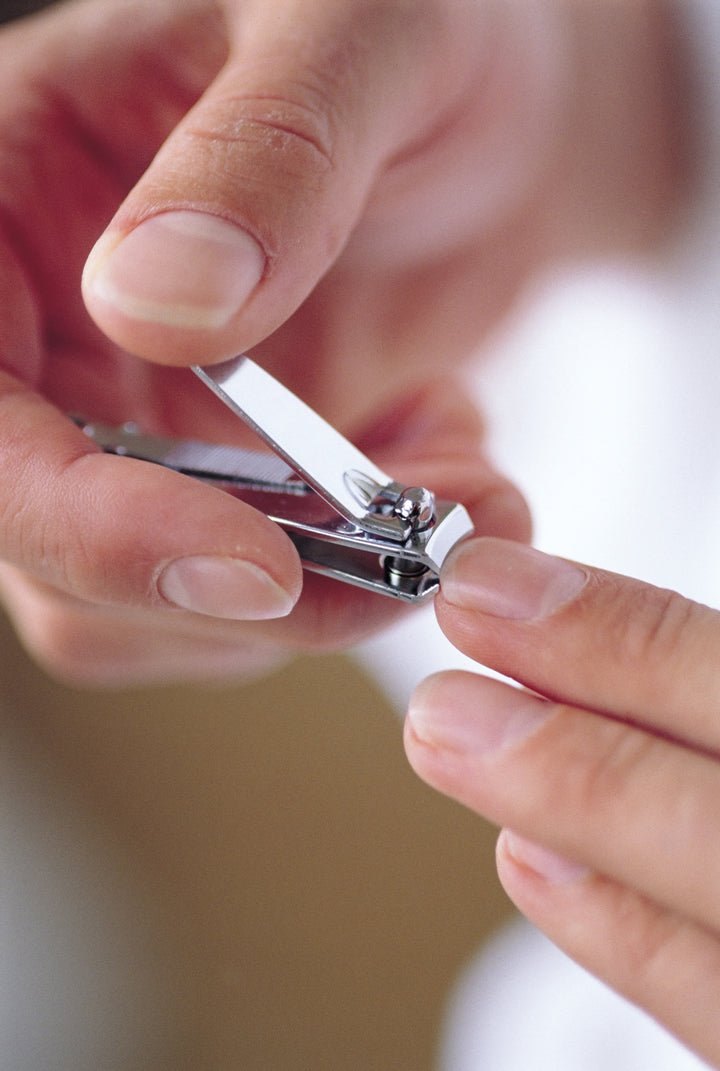 Man giving himself an at-home manicure, clipping his nails