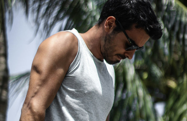 Close up of fit handsome man exercising in the sun, white vest, sunglasses, palm tree