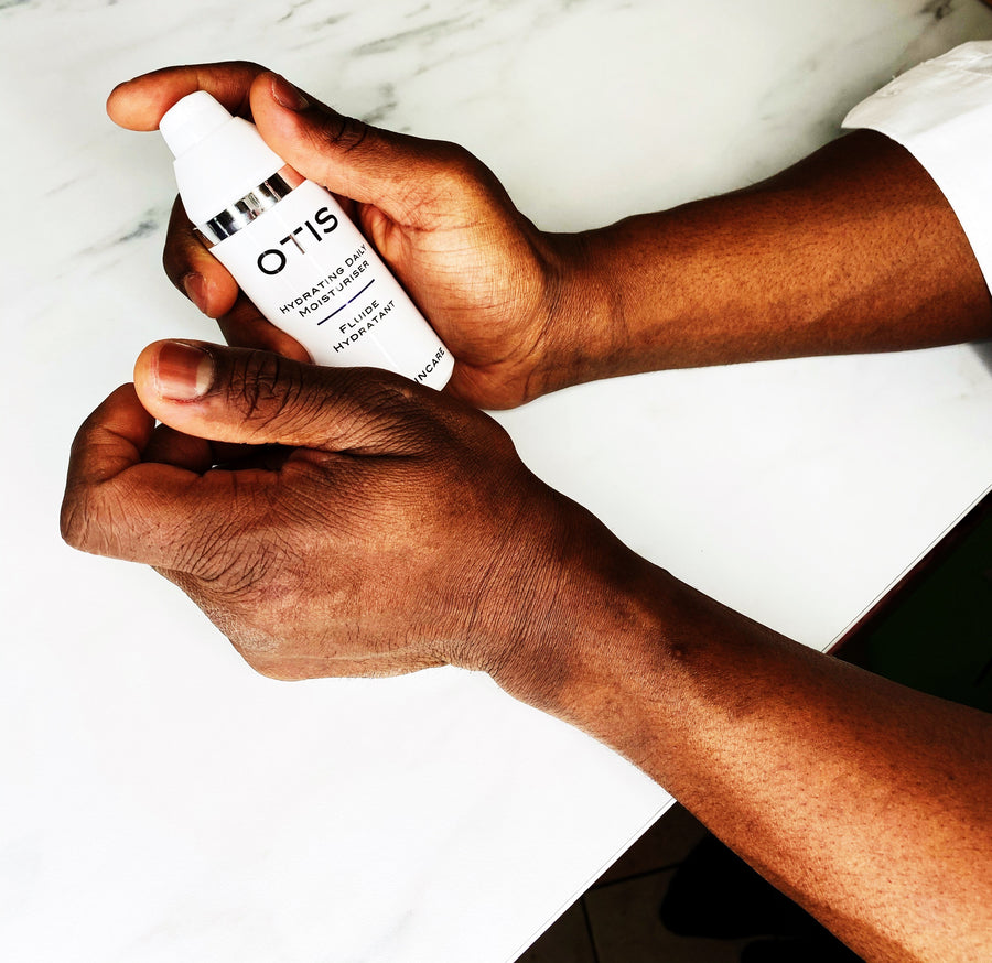 Close up of black man holding OTIS Hydrating Daily Moisturizer