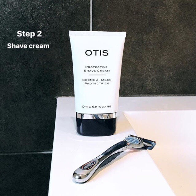 Tube of OTIS Protective Shave Cream with chrome razor against charcoal gray tiles